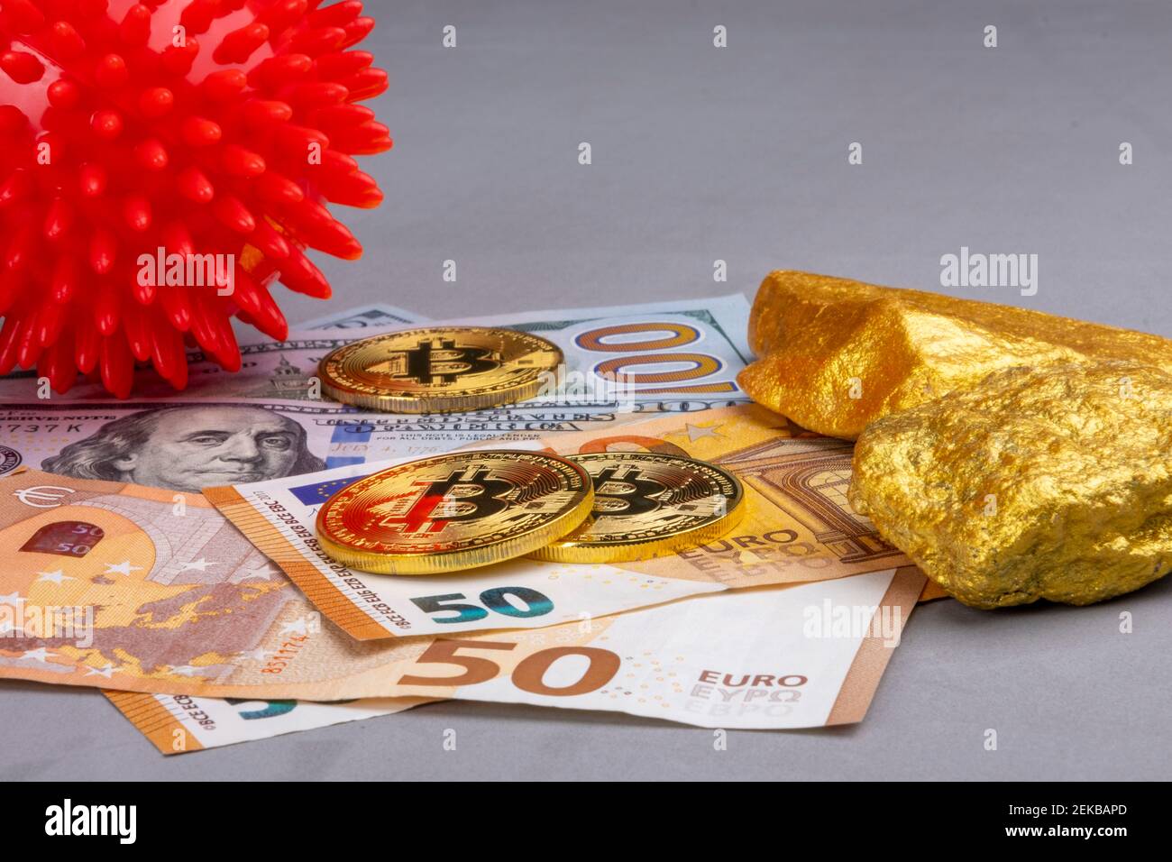 Kryptowährung, Geld an den globalen Aktienmärkten vs. Covid-19 Wirtschaftskonzept: Ein rotes Coronavirus neben Bitcoin und Goldstücken, EURO und US-DOLLAR Stockfoto