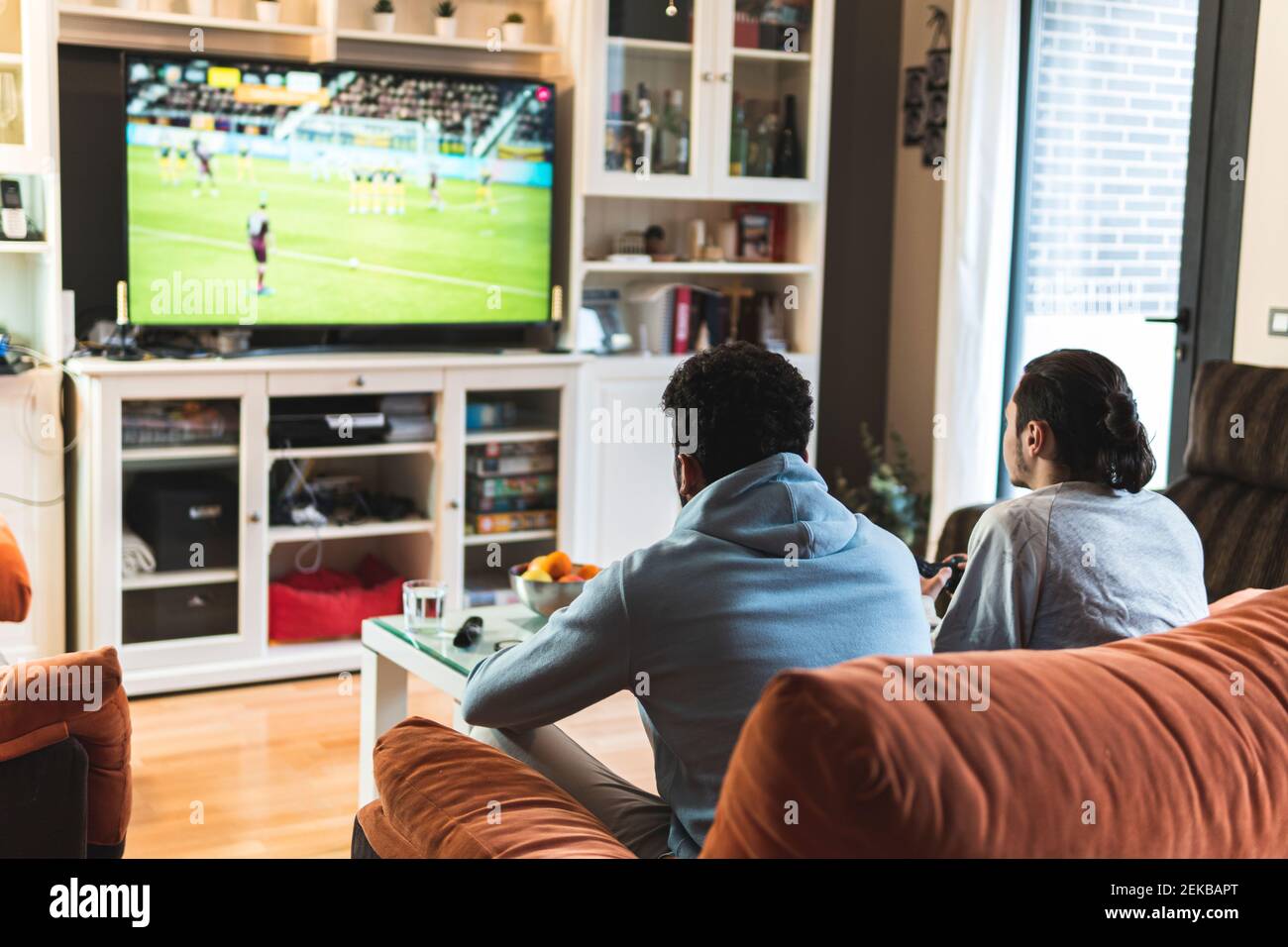 Junge männliche Freunde spielen Fußballspiel im Fernsehen im Leben Zimmer zu Hause Stockfoto