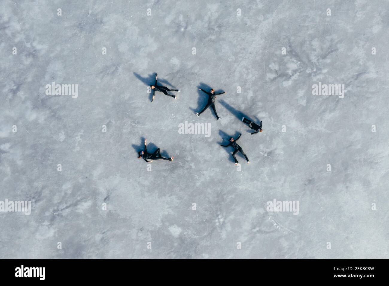 Luftaufnahme einer Gruppe von Eisläuferinnen, die zusammen auf liegen Oberfläche des gefrorenen Sees Stockfoto