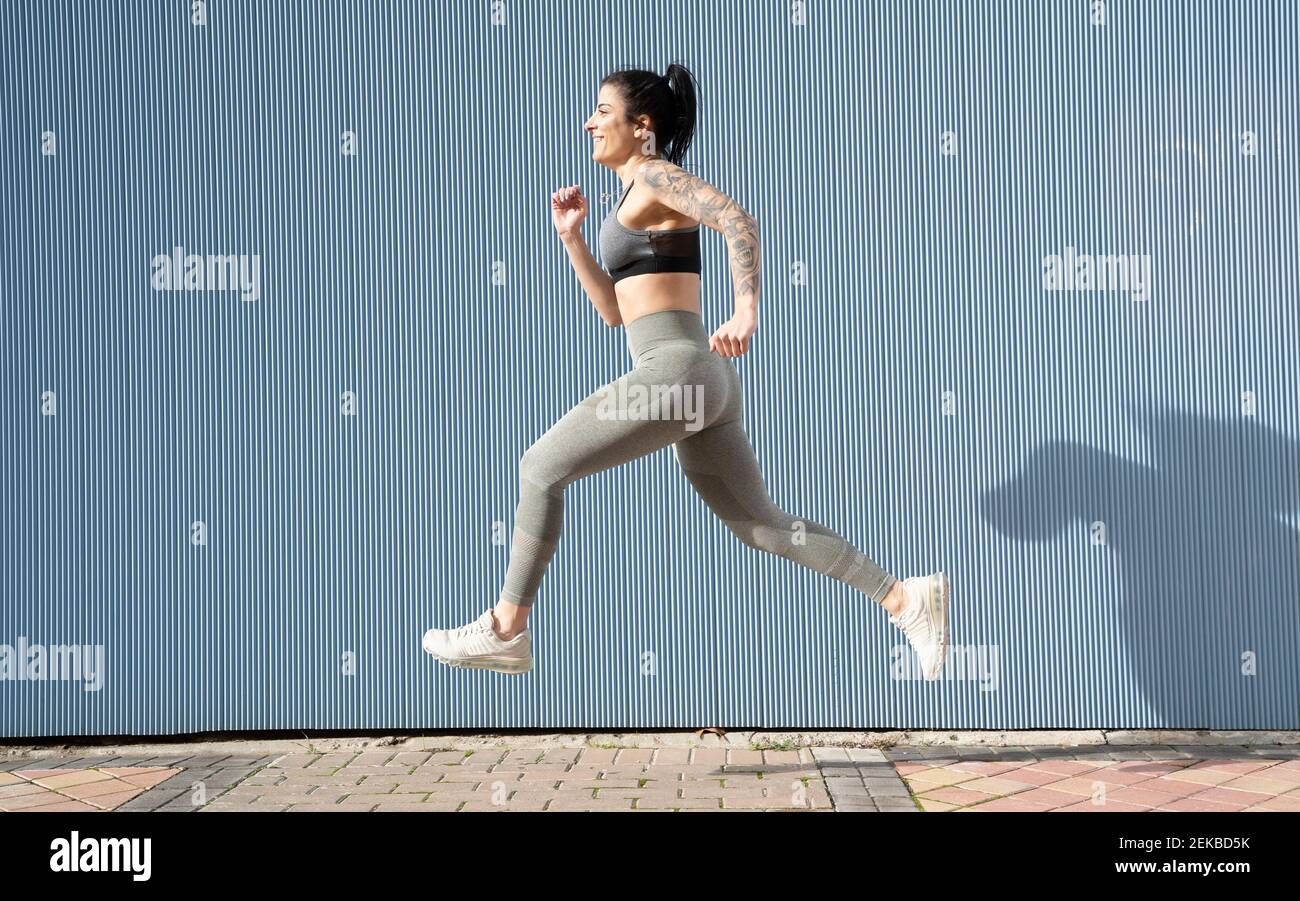 Frau mit mittlerem Erwachsenen, die an der blauen Wand auf dem Fußweg läuft Stockfoto