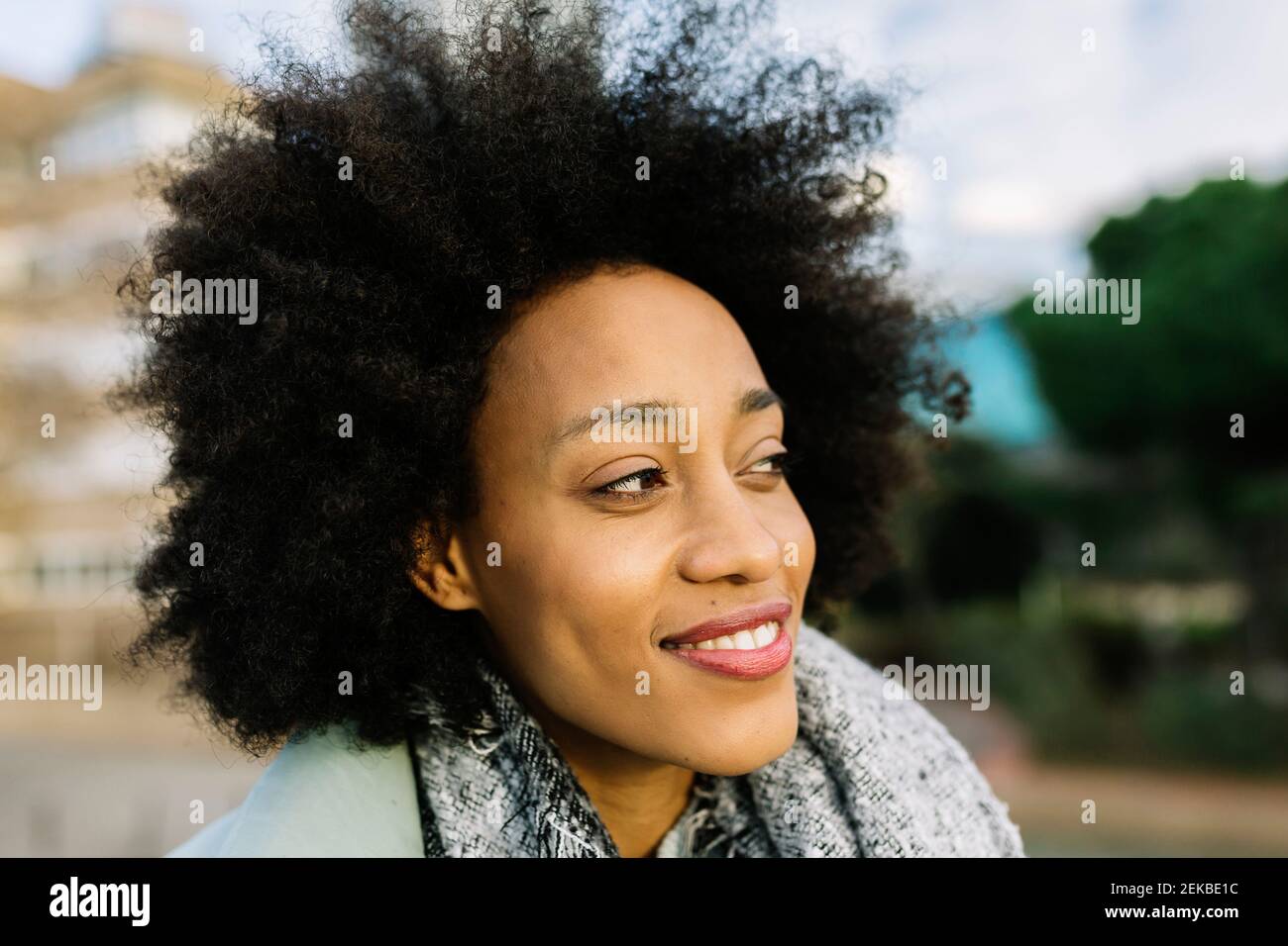 Afro-Frau lächelt, während sie draußen wegschaut Stockfoto Afro-Frau lächelt, während sie draußen wegschaut Stockfoto