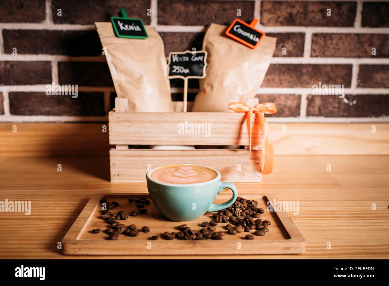 Kaffee mit Latte-Kunst inmitten von Kaffeebohnen auf Holztablett Stockfoto
