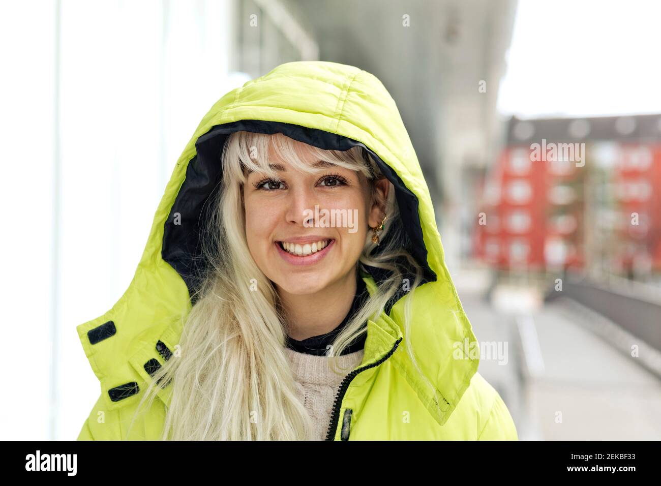 Nahaufnahme einer lächelnden jungen Frau mit gelbem Wintermantel Stadt Stockfoto