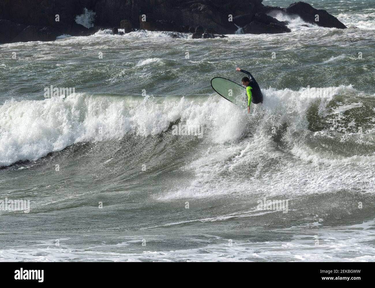 Mann, der auf Wellen surft, planscht im Meer am Broad Haven South Beach, Wales, Großbritannien Stockfoto