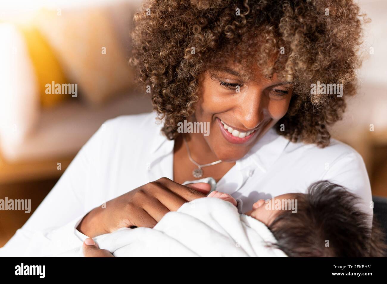 Glückliche Mutter, die das Baby anschaut, während sie zu Hause steht Stockfoto