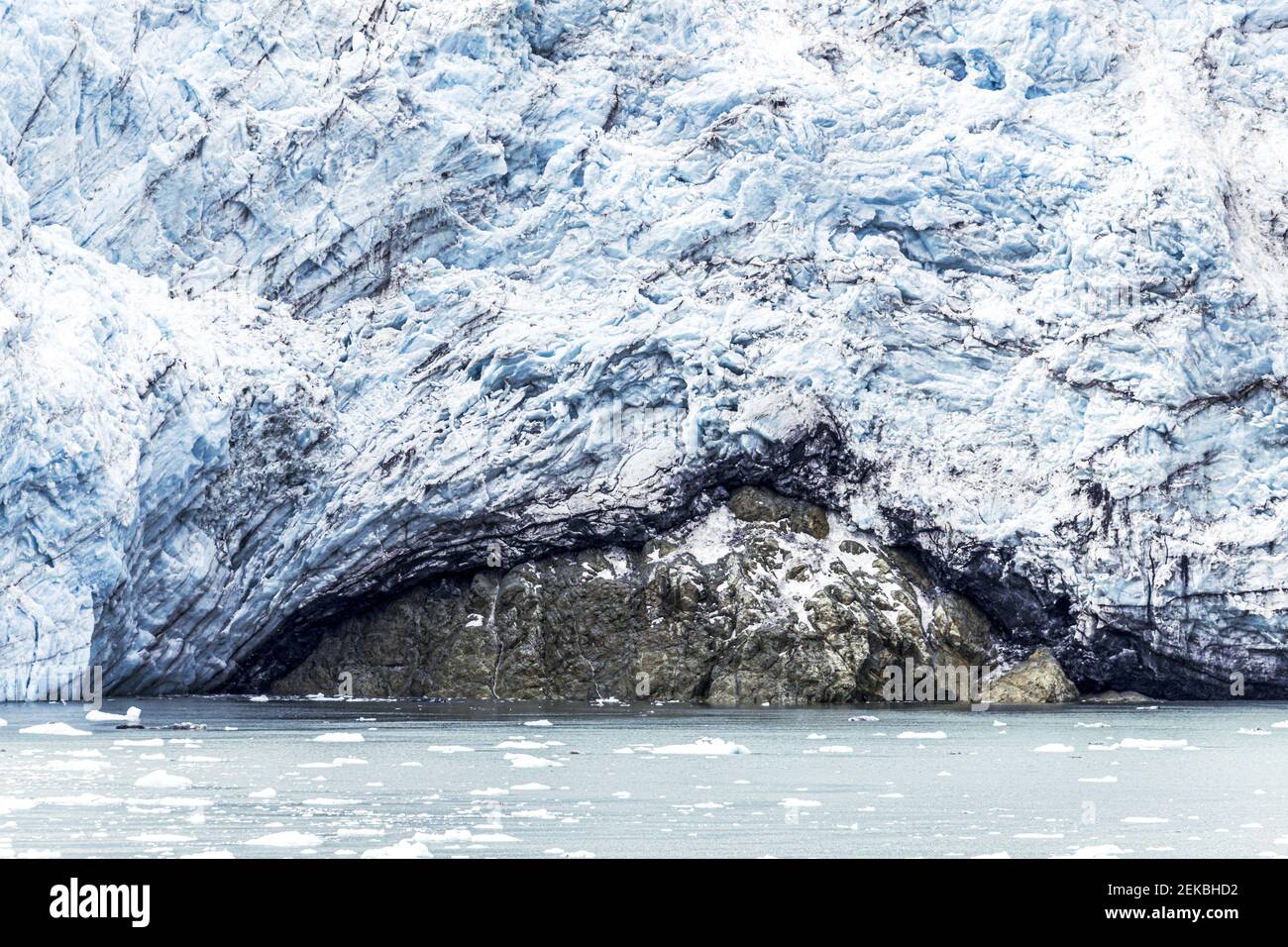 Die gebrochene Wand des Margerie Glacier im Tarr Inlet der Glacier Bay, Alaska, USA - zeigt Erosion eines darunterliegenden Felsens. Stockfoto