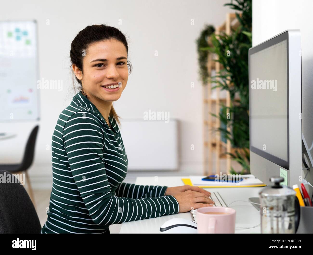 Glückliche weibliche professionelle sitzen am Schreibtisch am Computer bei der Arbeit Ort Stockfoto