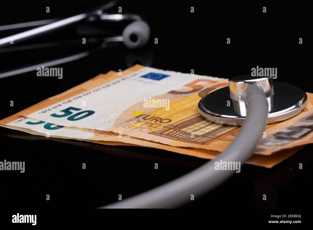 Gesundheits-, Versicherungs- und Wirtschaftskonzept: Europäische 50-EURO-Banknoten mit Stethoskop liegen auf schwarzem Hintergrund. Soziale Sicherheit Stockfoto