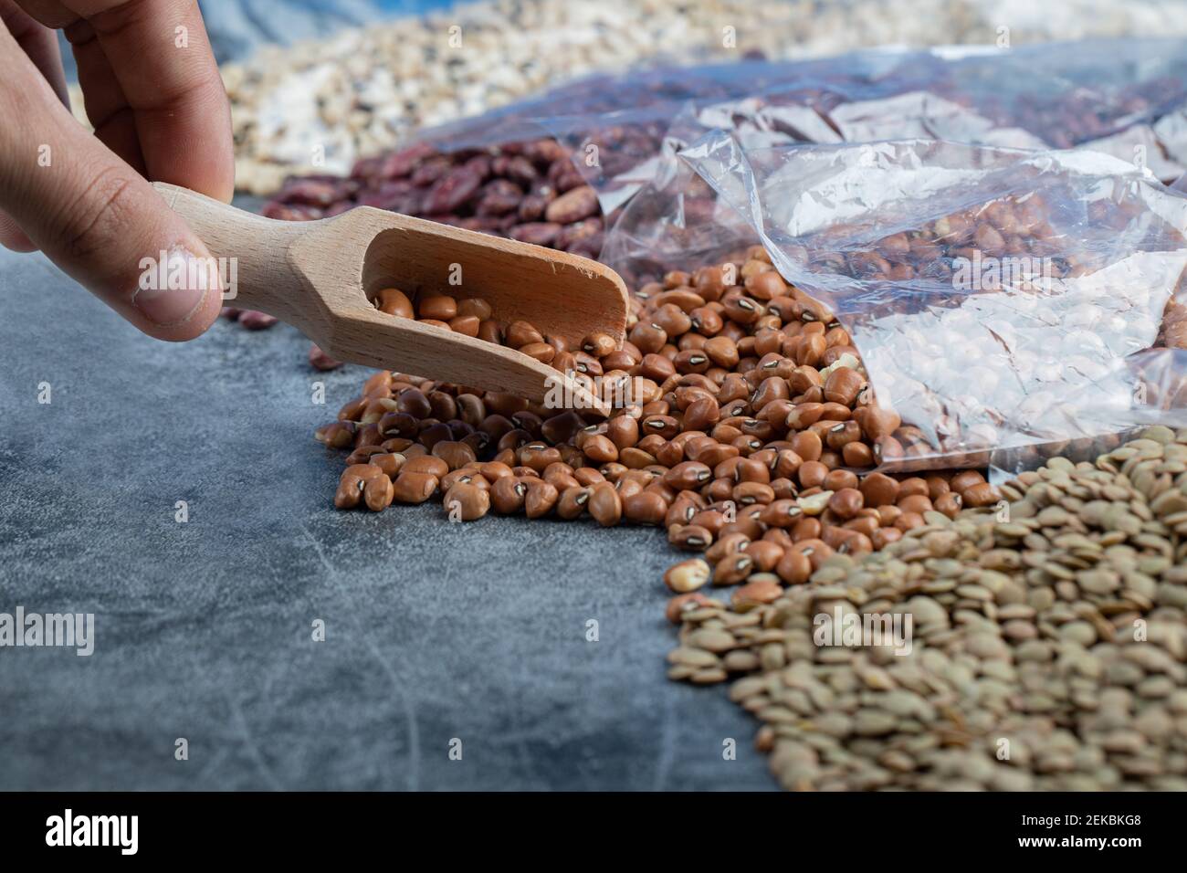 Weibliche Hand nimmt rote Bohnen aus Marmor Hintergrund Stockfoto