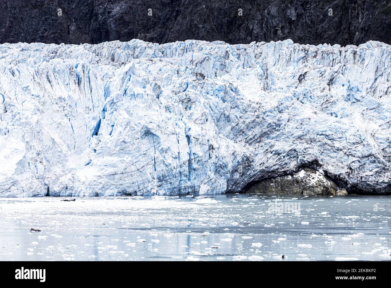 Die gebrochene Wand des Margerie Glacier im Tarr Inlet der Glacier Bay, Alaska, USA - zeigt Erosion eines darunterliegenden Felsens. Stockfoto