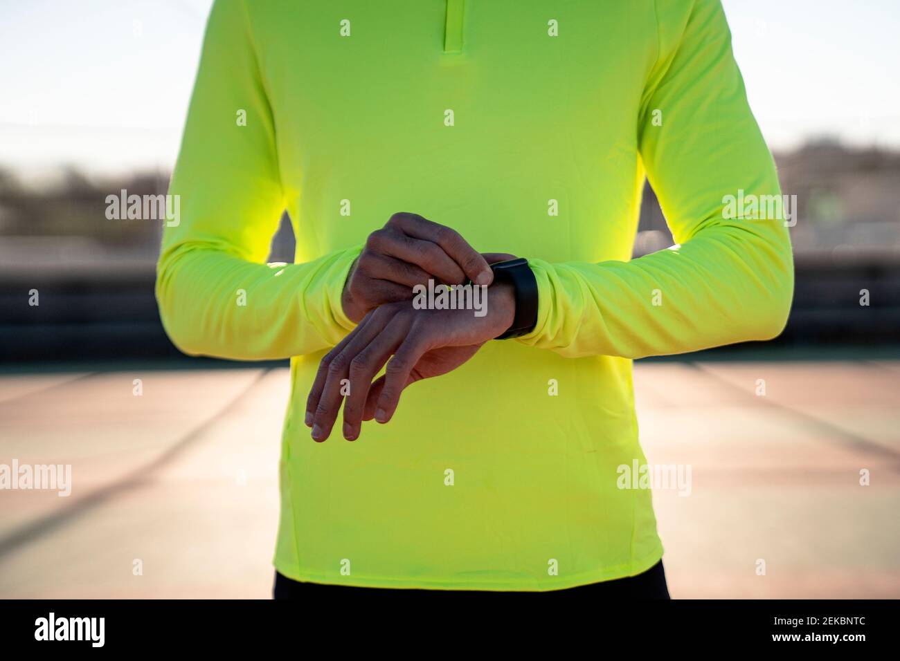 Männlicher Athlet, der die Zeit auf dem Sportplatz an sonnigen Tagen überprüft Stockfoto