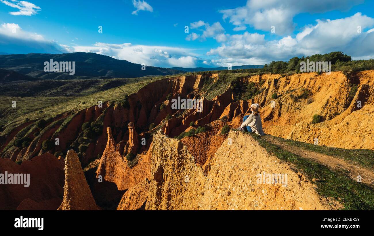 Hikerin sitzt auf Carcavas gegen Himmel in Valdepenas de la Sierra, Spanien Stockfoto