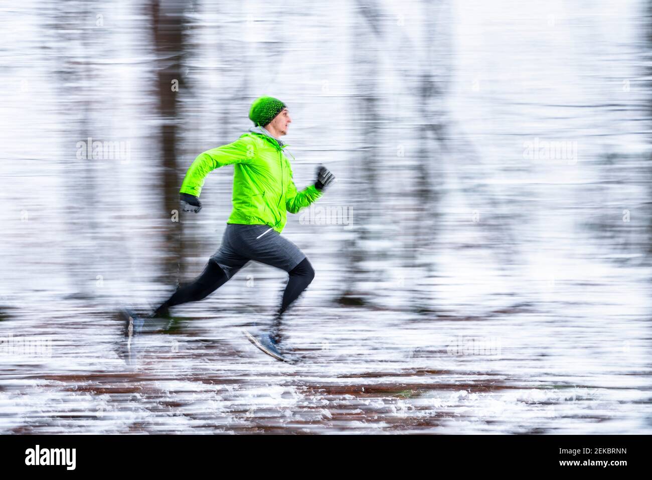 Junger Sportler läuft in Geschwindigkeit im Wald bei kalter Temperatur Stockfoto