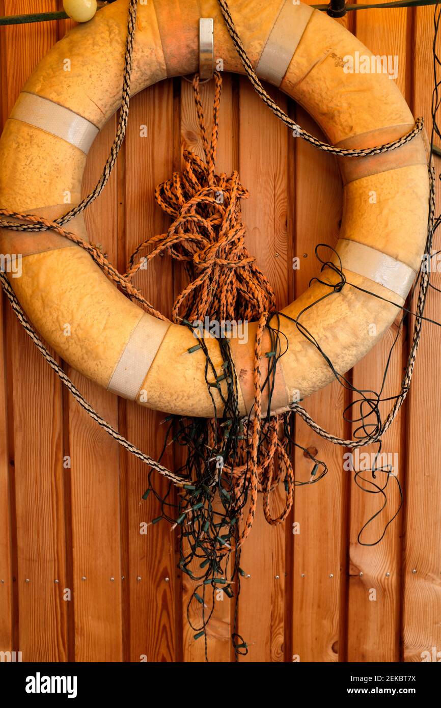 Rettungsgurt, Seile und Weihnachtslichter hängen an der Holzwand Stockfoto