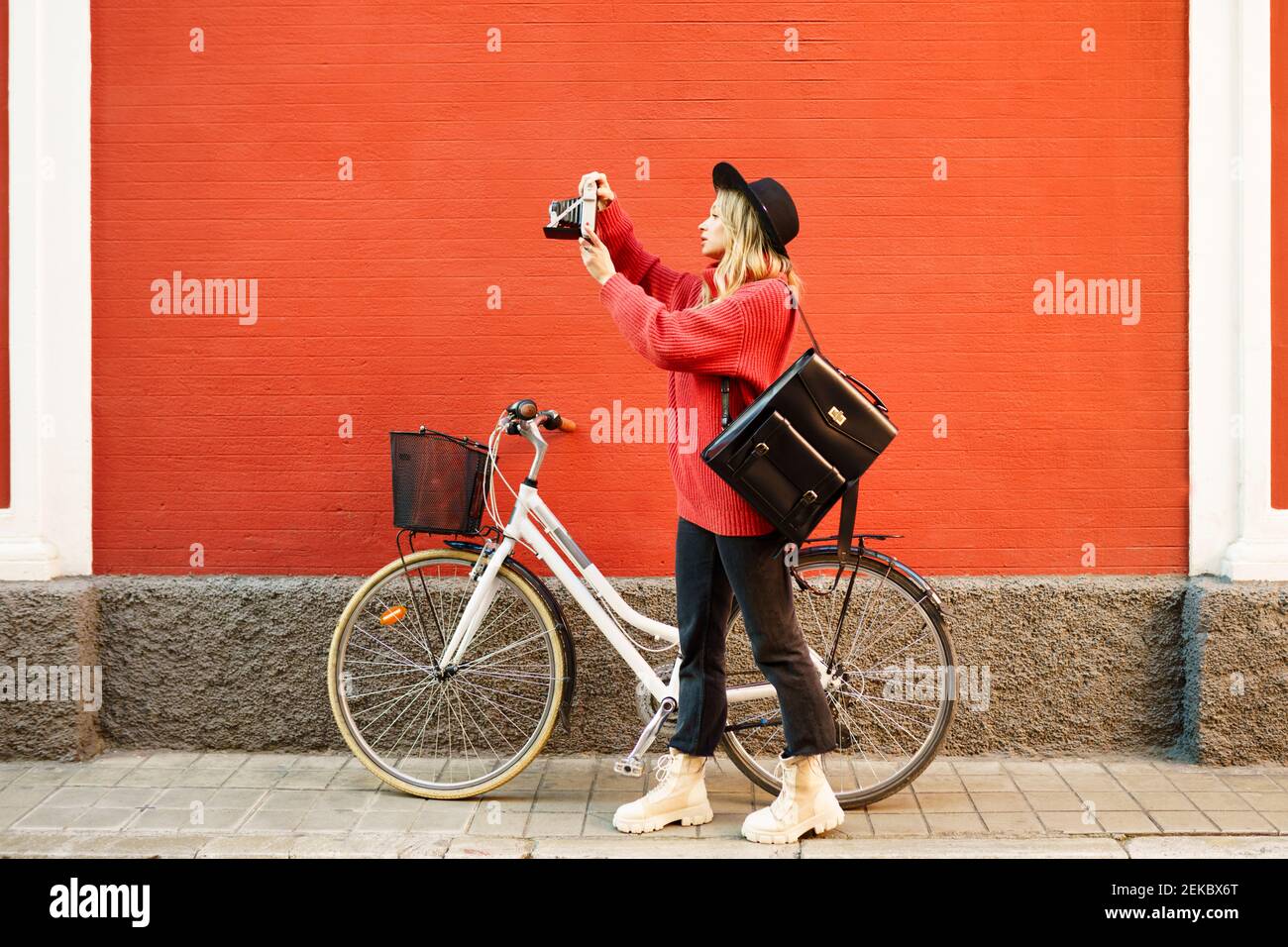 Frau mit Vintage-Kamera, während sie auf dem Fußweg steht Stockfoto Frau mit Vintage-Kamera, während sie auf dem Fußweg steht Stockfoto