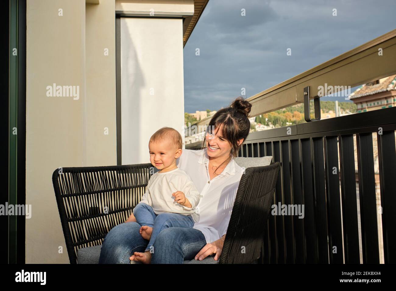 Mutter und Tochter sitzen zusammen im Sessel auf dem Balkon Stockfoto