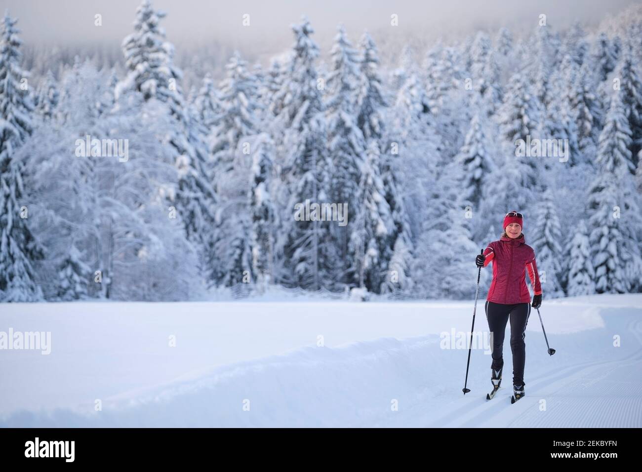 Frau trägt Warn Kleidung Skifahren mit Skistock auf Schnee Stockfoto