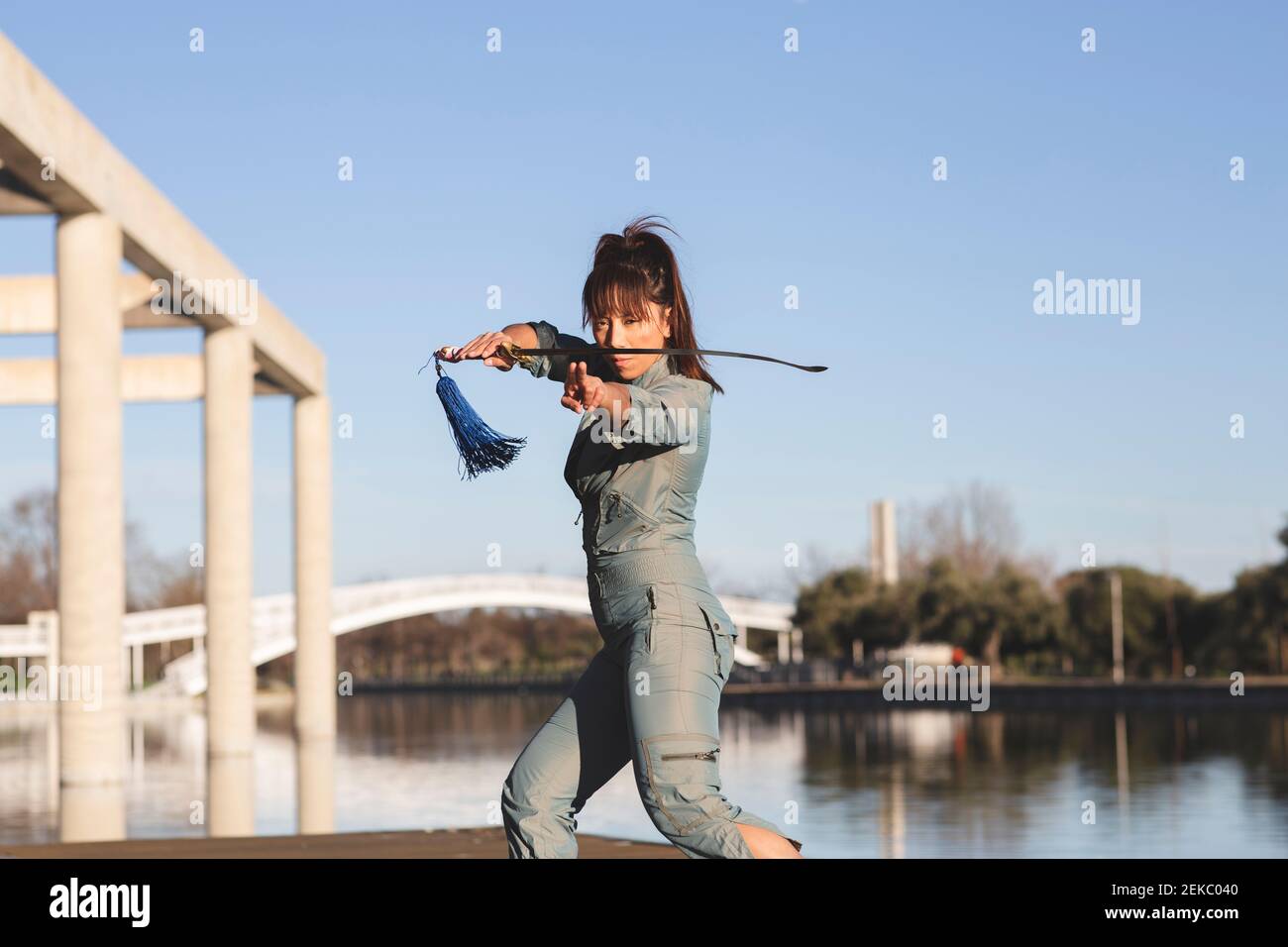 Selbstbewusste Athletin übt Kampfkunst mit Schwert gegen See Im Park Stockfoto