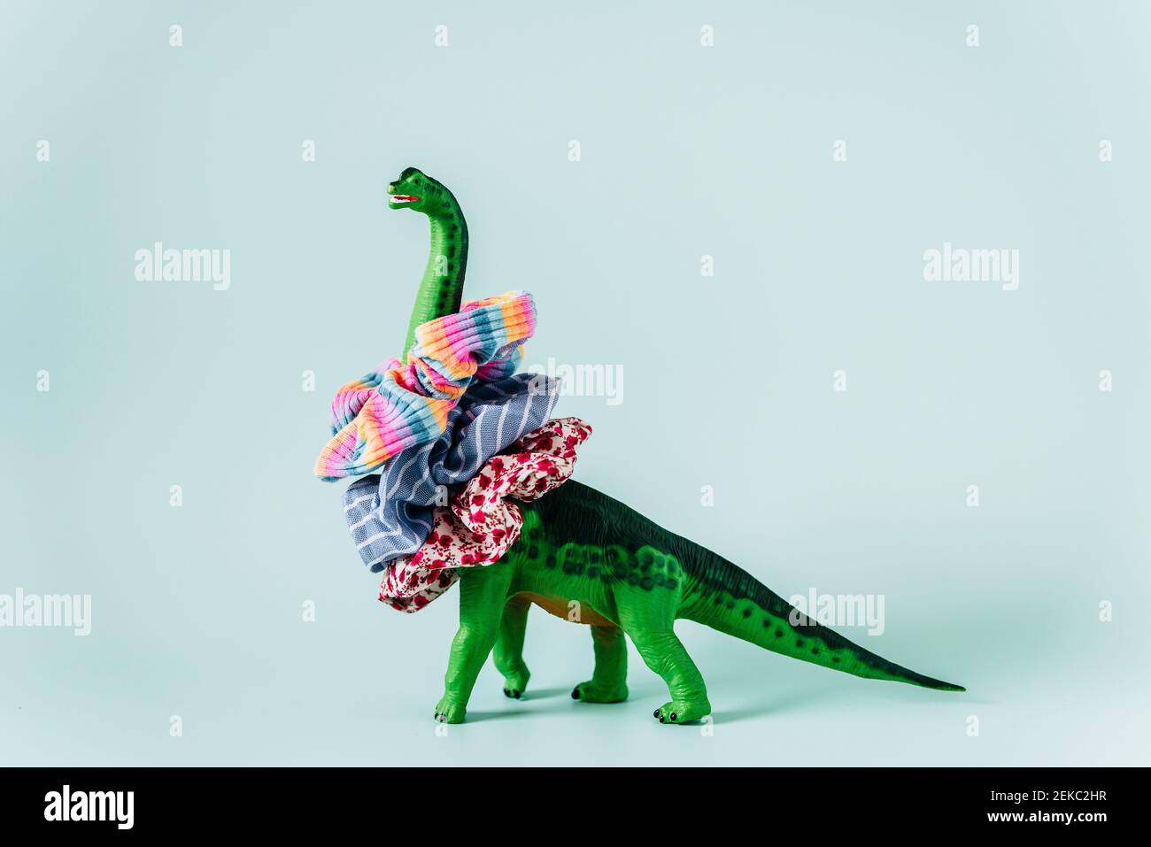 Diplodocus Dinosaurier Spielzeug mit Scrunchies Haarbänder um seinen Hals Auf mintgrünem Hintergrund Stockfoto