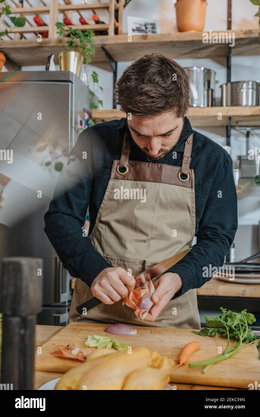 Koch schält Zwiebel, während er in der Küche steht Stockfoto