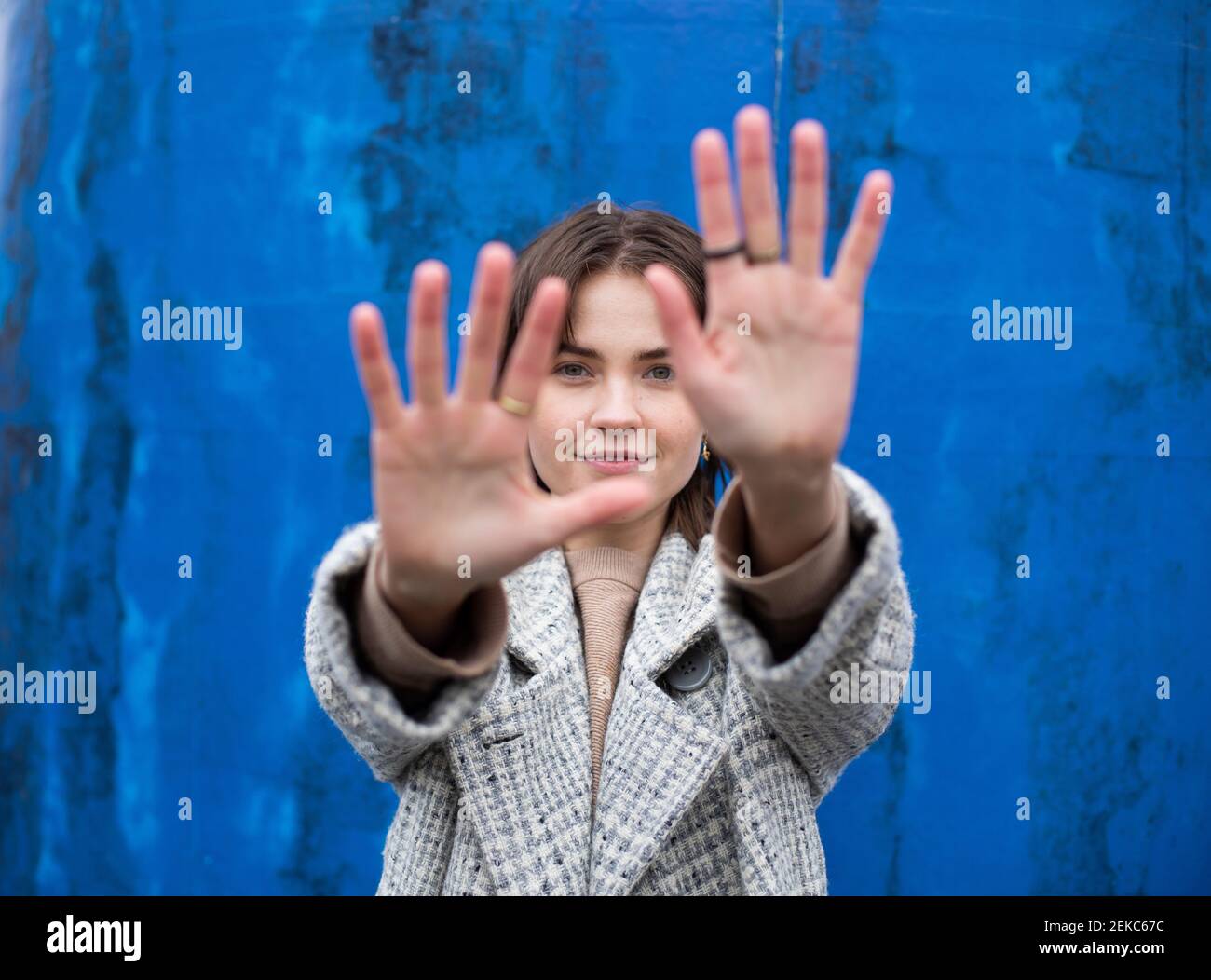 Schöne Frau zeigt Stop-Zeichen gegen blaue Wand Stockfoto