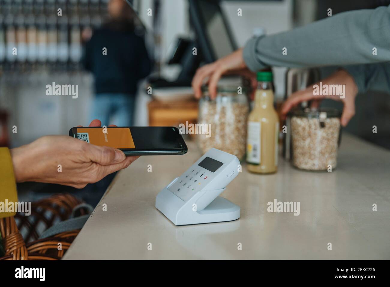 Ein reifer Kunde mit Mobiltelefon, das über einen Barcode-Scanner bezahlt Im Einzelhandel Stockfoto