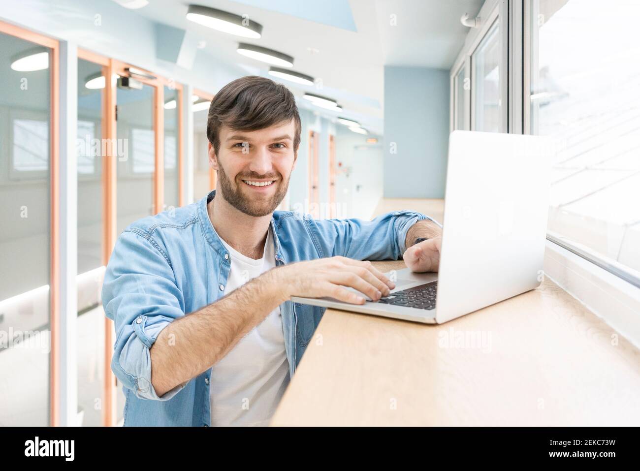 Glücklich kreative männliche Profi mit Laptop im Flur zu stehen Arbeitsplatz Stockfoto