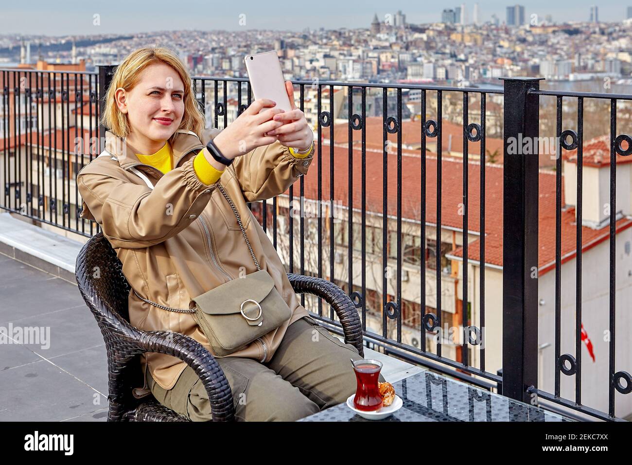 Teetrinken auf dem Dach des Hotels mit Blick auf das Stadtbild von Istanbul, junge europäische Frau, die Fotos von sich macht oder Selfies mit dem Smartphone macht. Stockfoto
