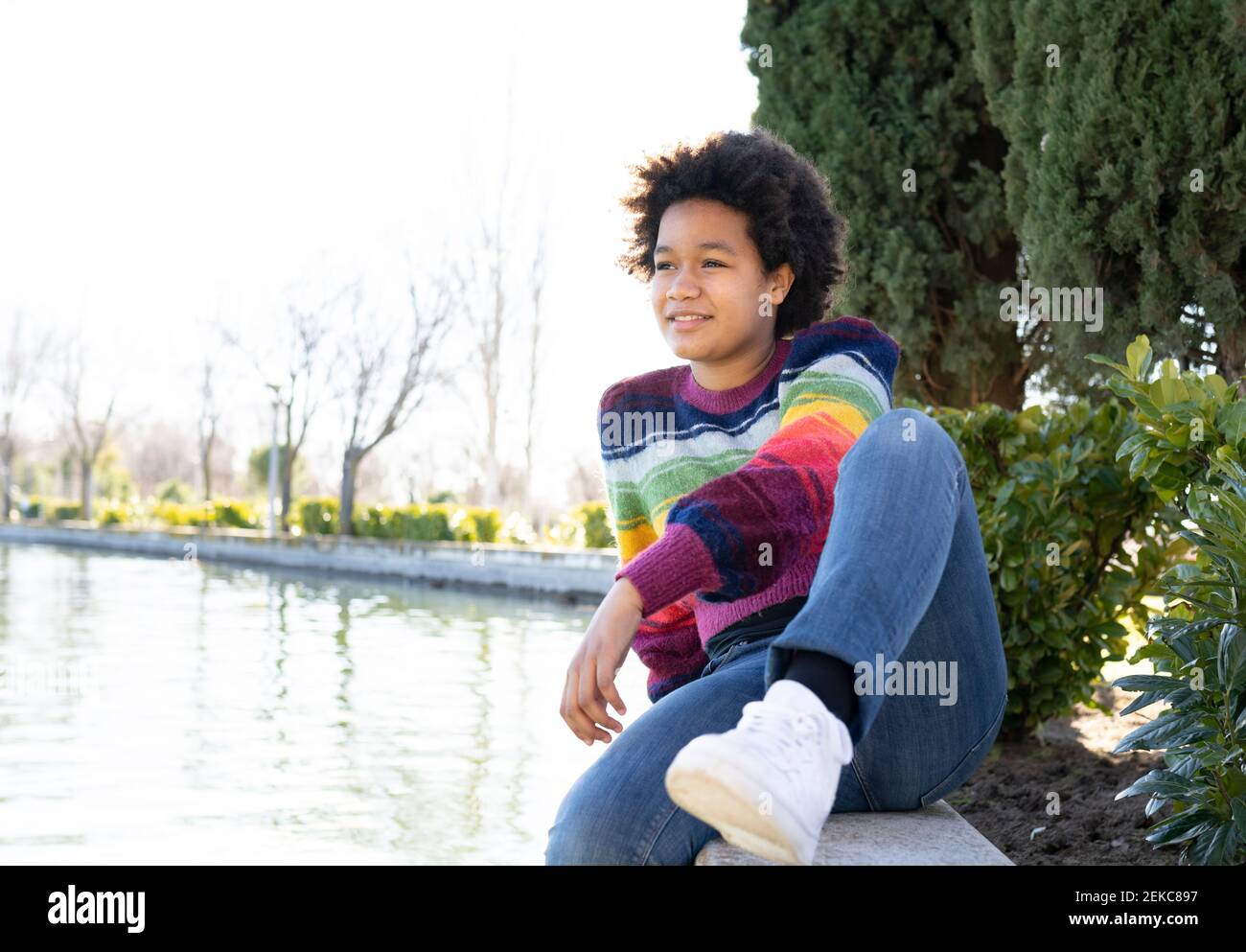 Nachdenklich Mädchen entspannen, während auf Stützmauer im Park sitzen Stockfoto