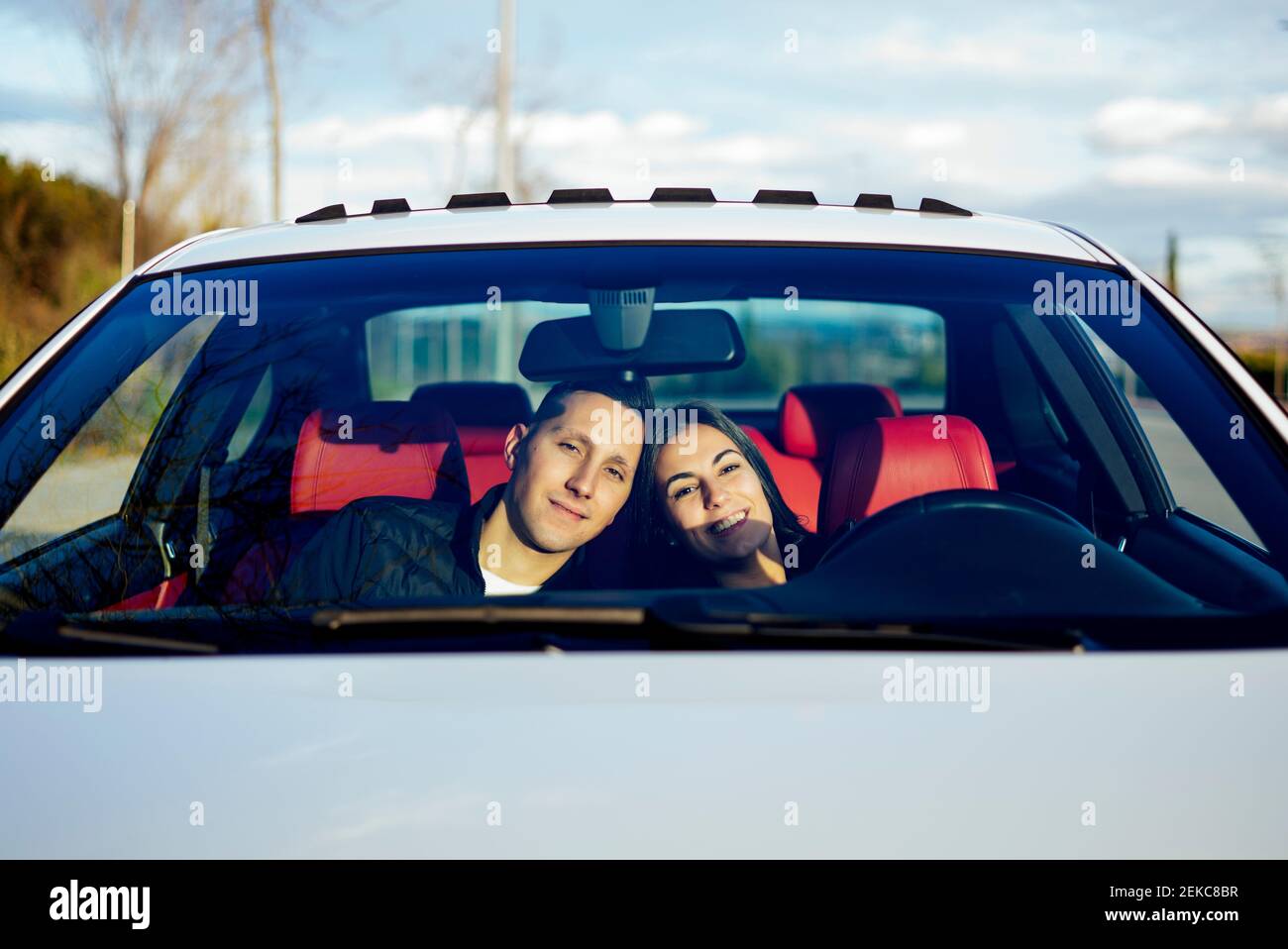 Junges Paar lächelt, während sie im Auto sitzt Stockfoto