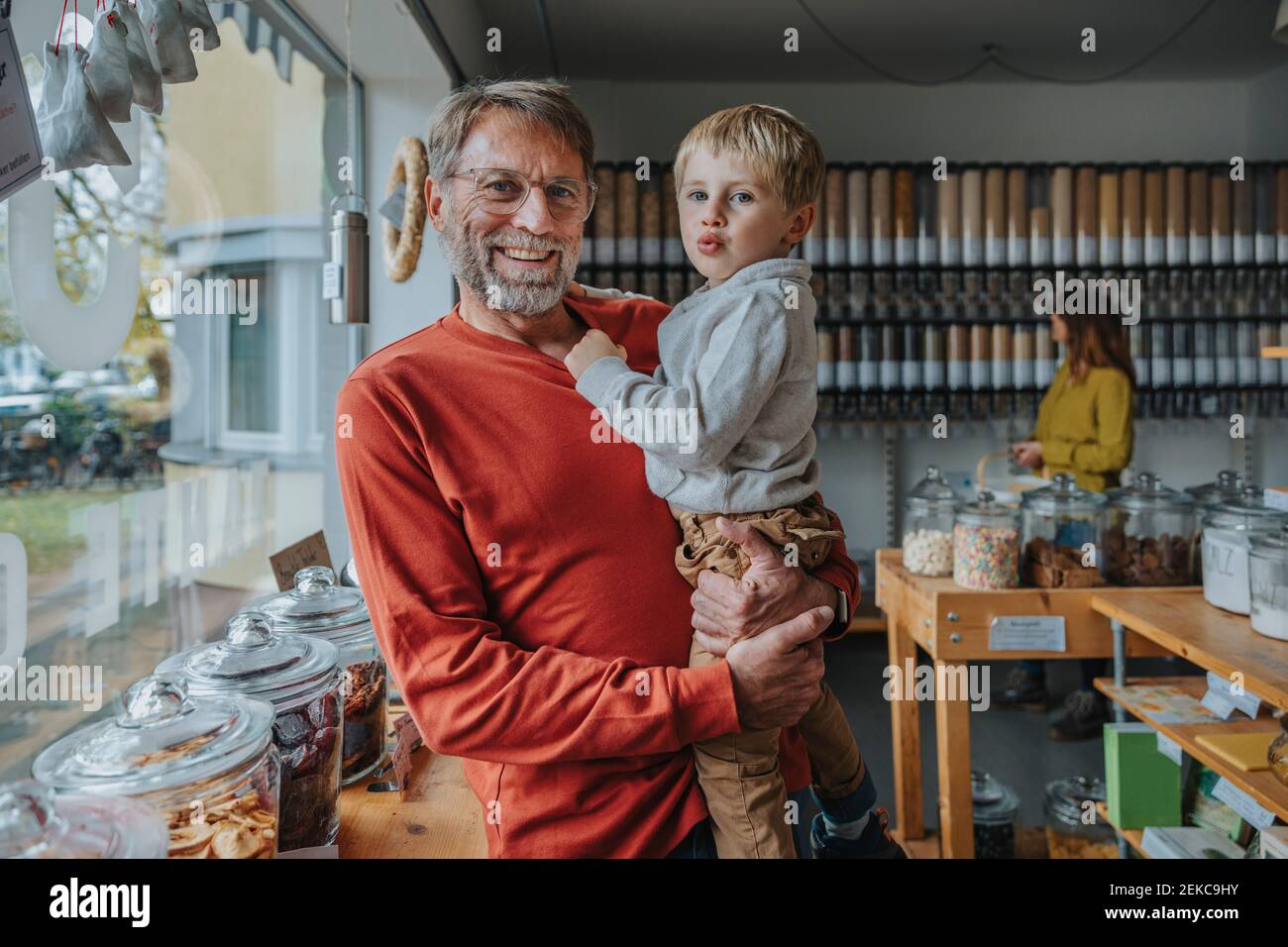 Reifer Vater trägt Sohn, während im Einzelhandel Lebensmittelgeschäft stehen Stockfoto