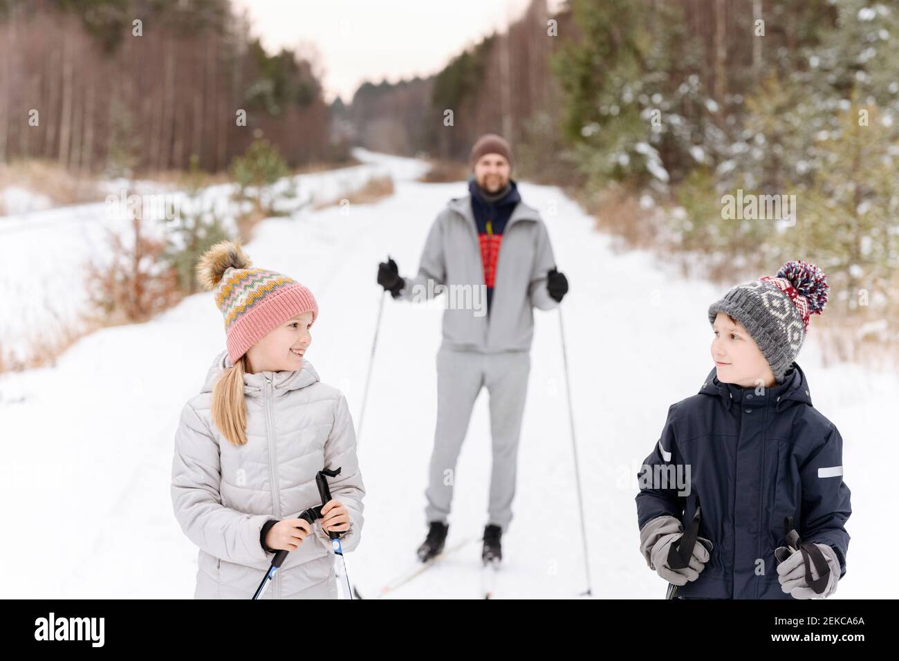Vater mit Kindern Skifahren auf verschneite Landschaft im Wald Stockfoto