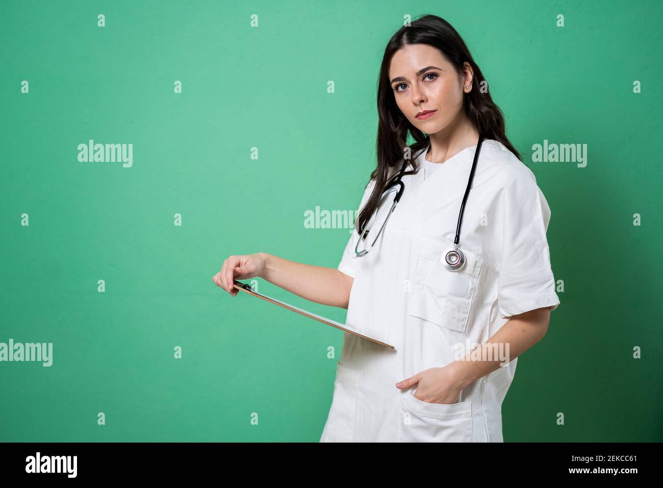 Selbstbewusste Ärztin mit Klemmbrett und Stethoskop um den Hals in studio Stockfoto