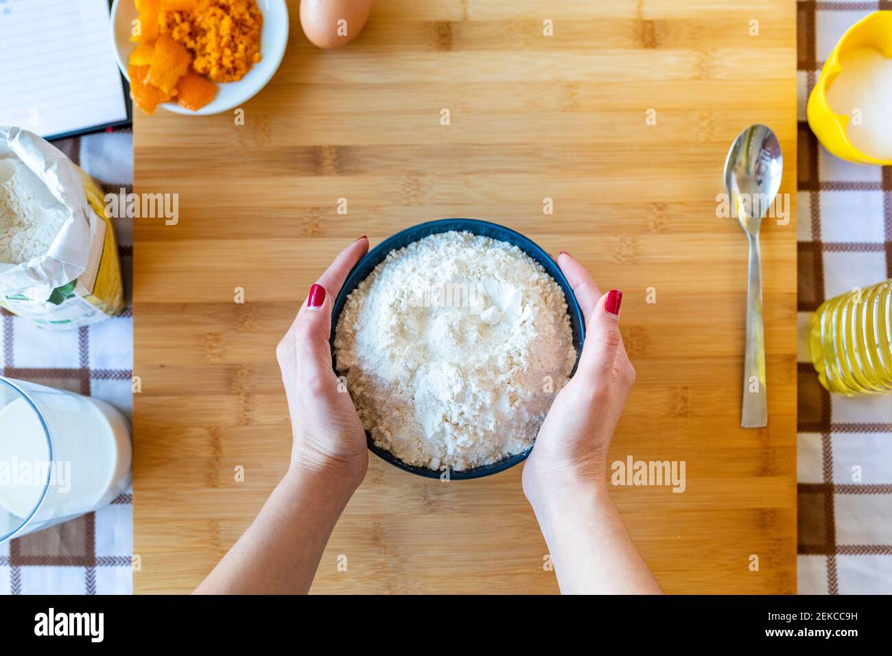 Frau mittleren Erwachsenen hält Mehl Schüssel auf Schneidebrett in Küche Stockfoto