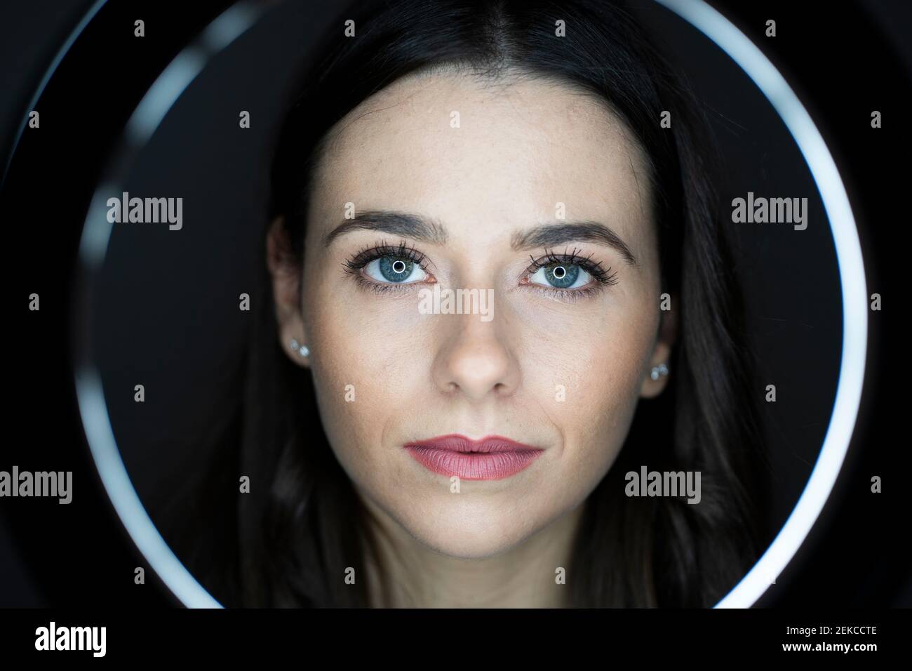 Frau mit rosa Lippenstift durch Ringlicht im Studio gesehen Stockfoto