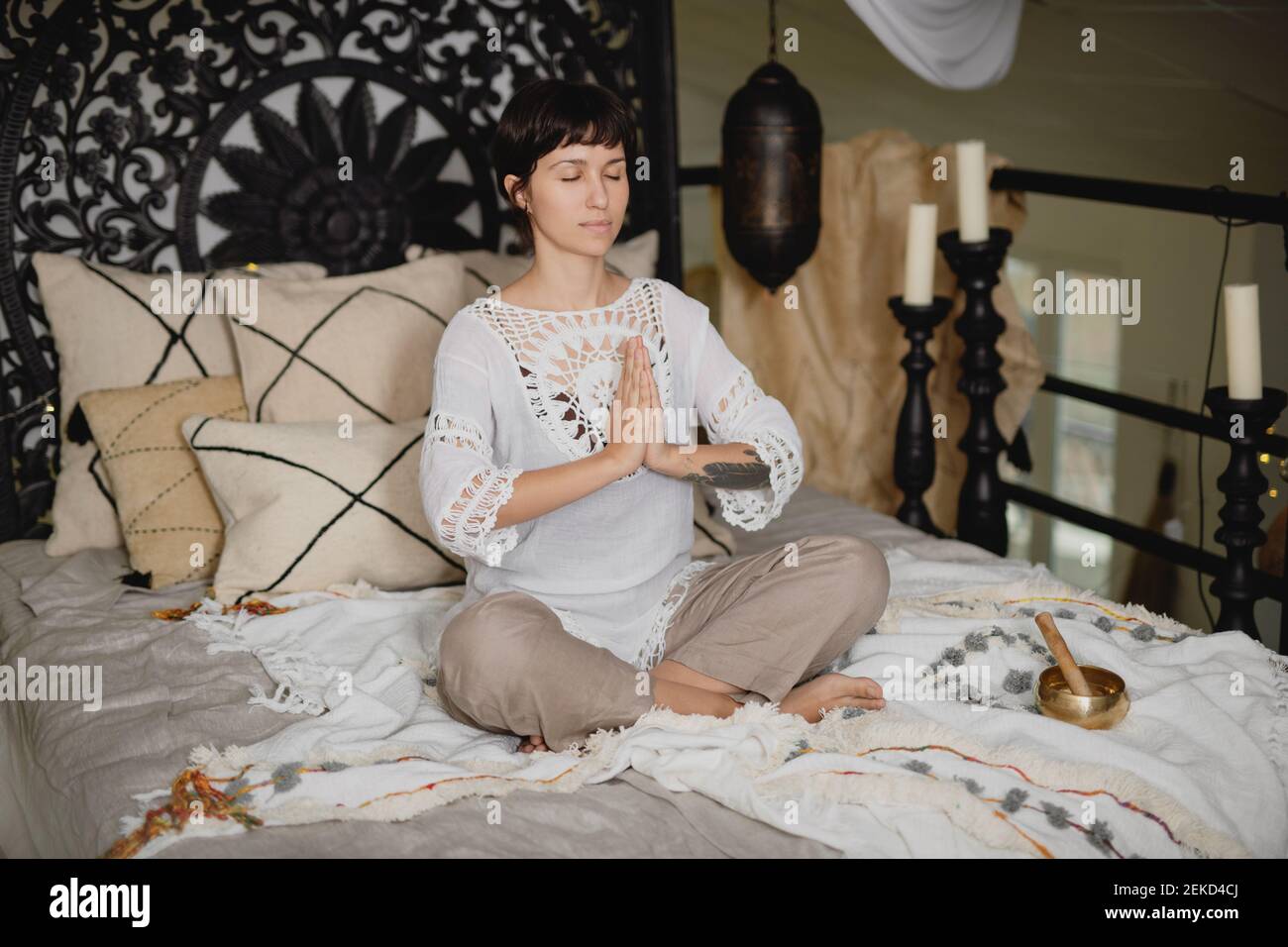 Junge schöne Frau praktiziert Yoga sitzen in Namaste Pose auf dem Bett zu Hause. Stockfoto