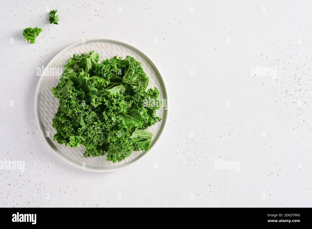 Schüssel mit frischem grünen gehackten Grünkohl auf hellgrauem Steinhintergrund, Draufsicht. Zutat für die Herstellung von gesunden Salat. Sauberes Essen, Entgiftung oder Diät-Konzept. M Stockfoto