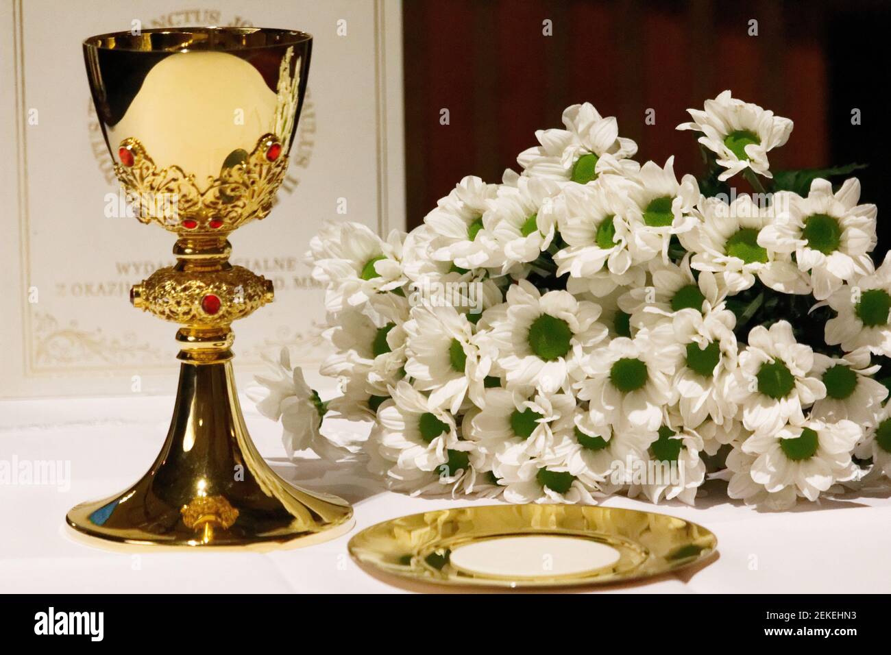 Ein goldener Kelch mit weißen Blumen und bibel. Religion. Christentum. Heilige Kommunion. Katholisches Thema. Stockfoto