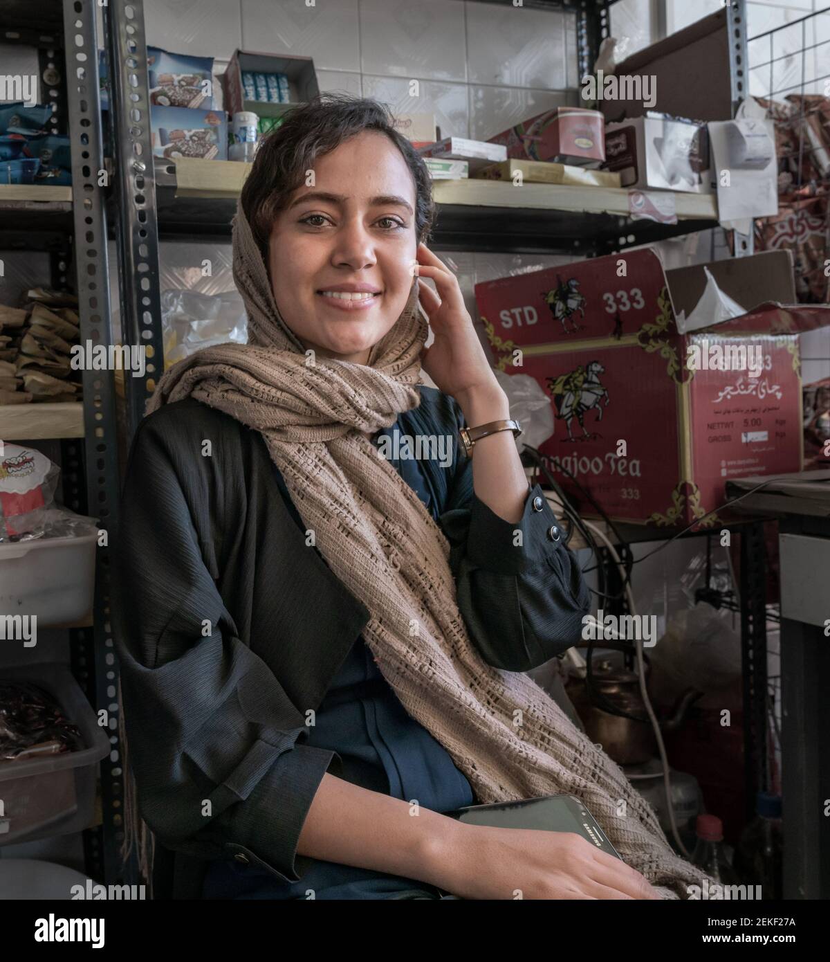 Junge iranische Dame in einem traditionellen Kleid mit einem Kopftuch sitzt im Lebensmittelgeschäft. Shiraz, Iran. Stockfoto