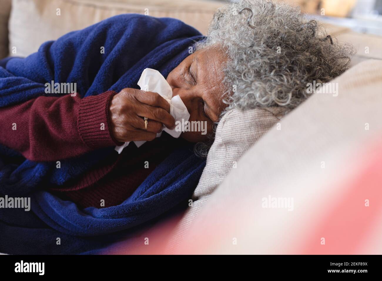 Kranke afroamerikanische ältere Frau, die auf der Couch liegt Stockfoto
