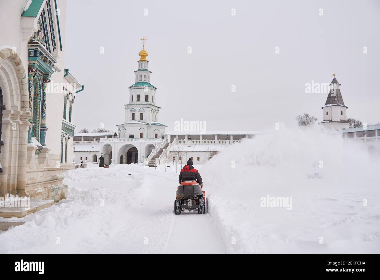 Russland, Region Moskau, Februar 2021.EIN warm gekleideter Mann auf einem Schneepflug entfernt an einem frostigen Tag Schnee auf dem Gebiet des Klosters. Stockfoto