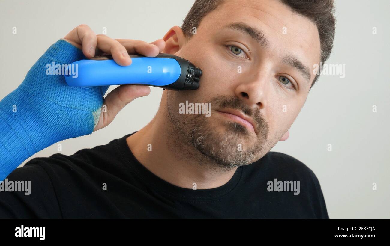 Der Mann rasiert seine Wange mit einem elektrischen Rasiermesser  Stockfotografie - Alamy