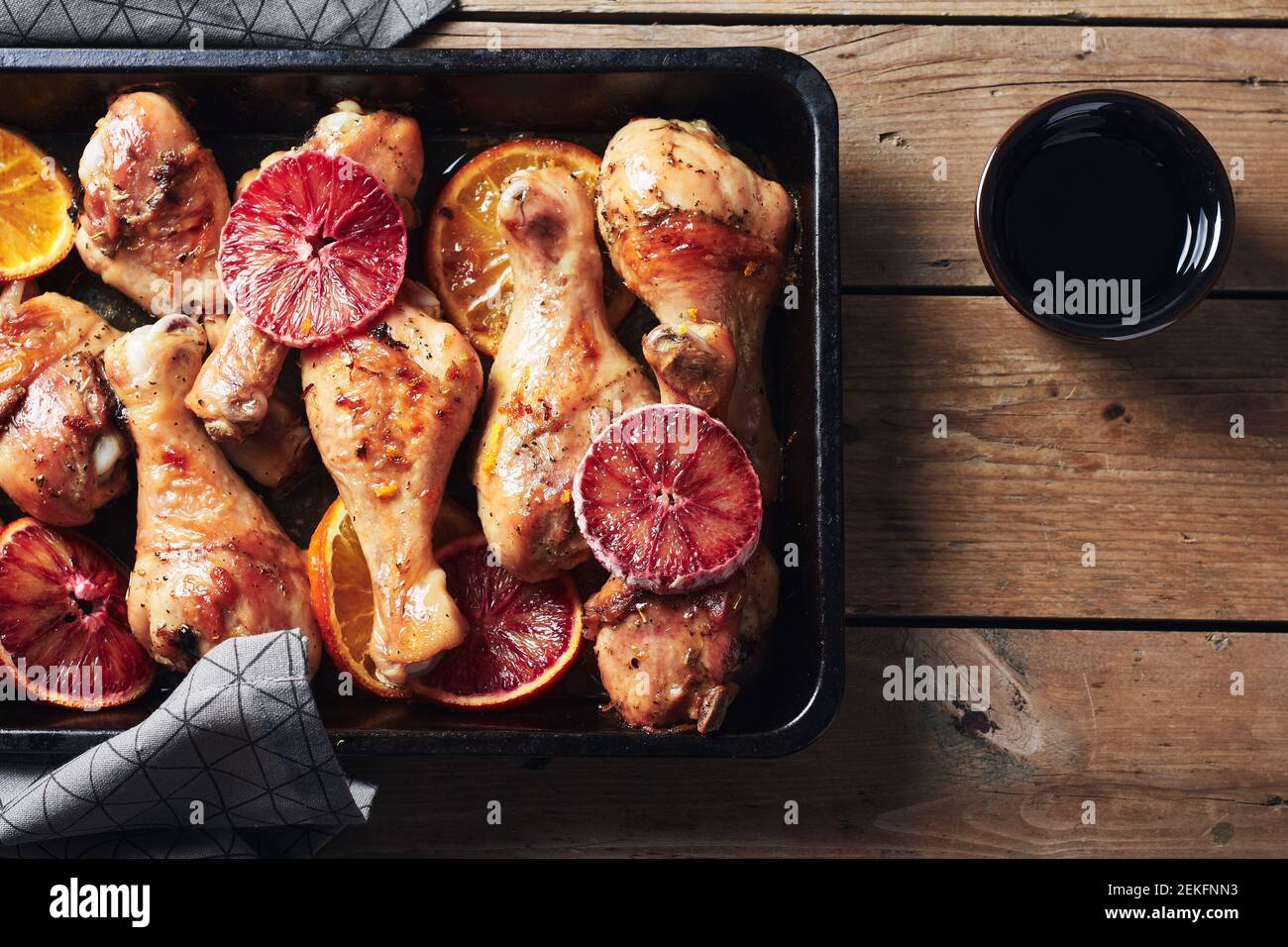 Würzen Sie gebratene Hähnchendrumstick in der Bratpfanne. Gebackene Hähnchenschenkel mit Orangen. Stockfoto