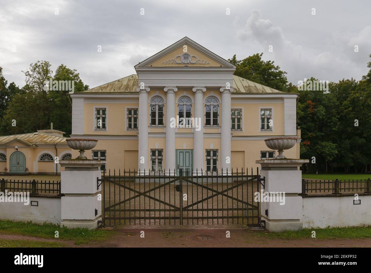 Vor dem Herrenhaus Kumna. Winziges mittelalterliches Gebäude, im neoklassizistischen Stil renoviert. Hellgelbe Wände, weiße griechische Säulen, Bogenfenster. Stockfoto