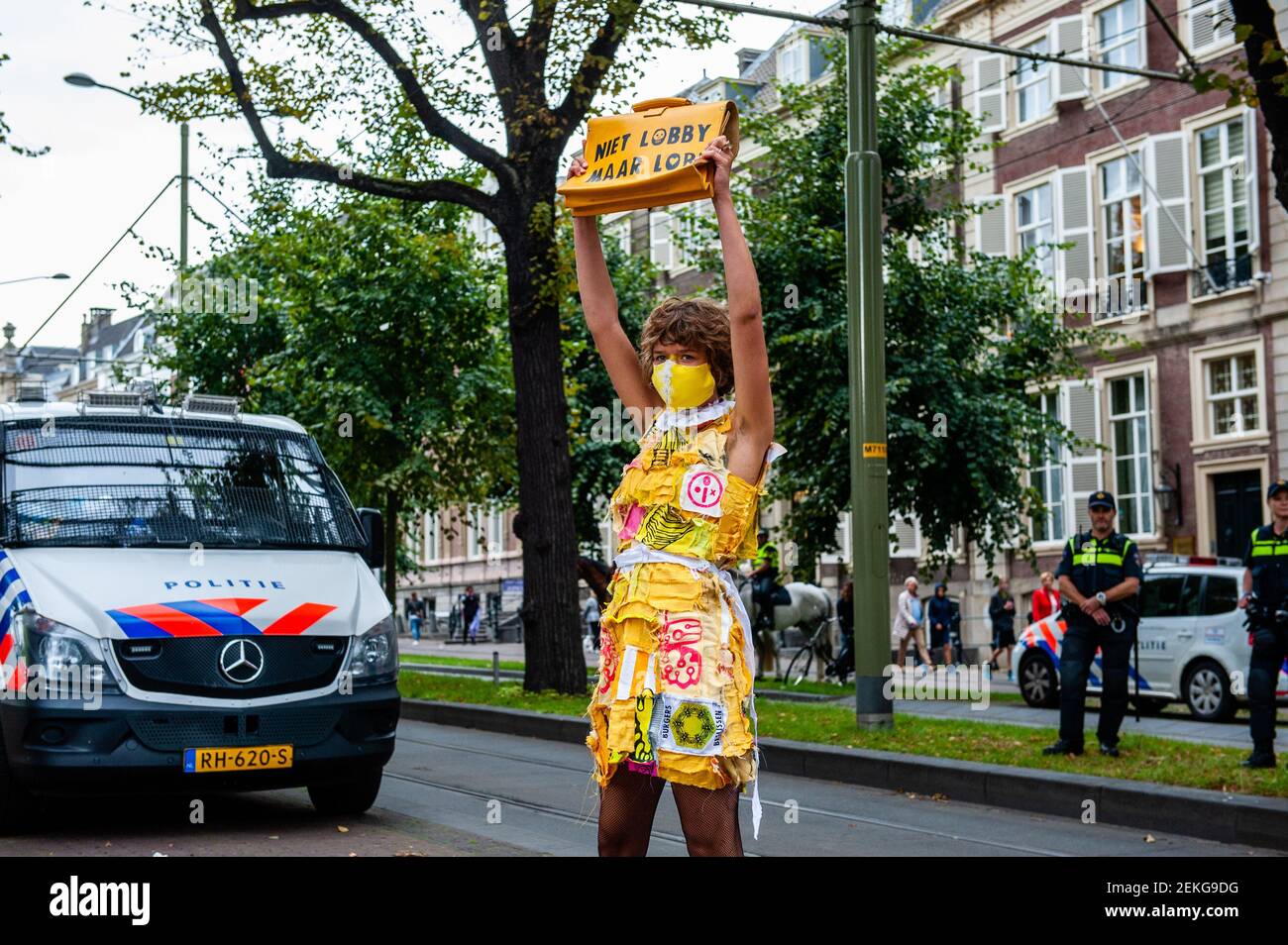 Eine weibliche XR-Modell posiert mit ihrer Tasche in der Nähe der niederländischen Polizei während der Modenschau. Vor dem Repräsentantenhaus in Den Haag wurde eine "XR Fashion Show" durchgeführt. Modelle trugen gelbe, schwarze und weiße bunte Second-Hand-Outfits, um die Kollektivität der Bienen zu symbolisieren, um zu zeigen, dass Denken und Arbeiten zusammen uns aus dieser Krise helfen können. (Foto: Ana Fernandez / SOPA Images/Sipa USA) Stockfoto