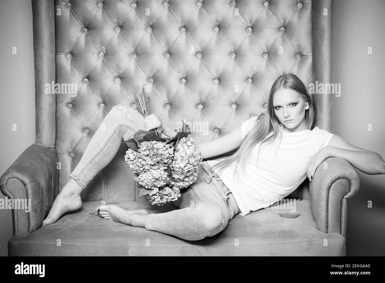 Mode Frau mit Blumen entspannen auf dem Sofa. Modischer Style. Beauty-Look. Frauentag. Stockfoto