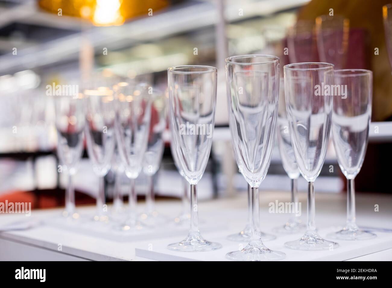 Reihen von glänzenden leeren hohen Gläsern mit Reflexen im Restaurant. Catering-Konzept.Set von leeren Weingläser in Reihen angezeigt. Vorbereitung für Stockfoto