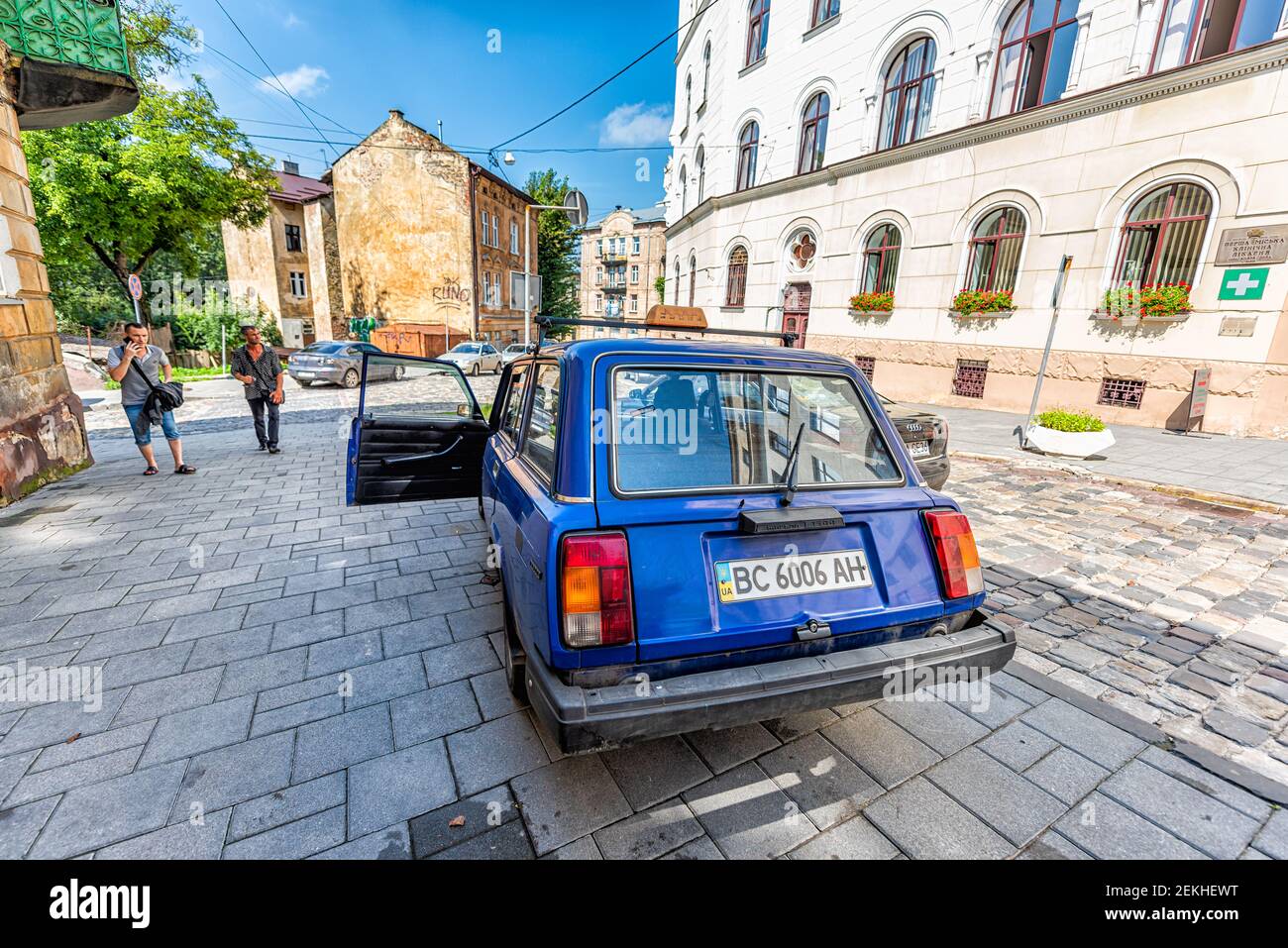 Lviv, Ukraine - 1. August 2018: Historische ukrainische Stadt in der Altstadt mit alten blauen Auto und Menschen auf der Straße im sonnigen Sommer Stockfoto