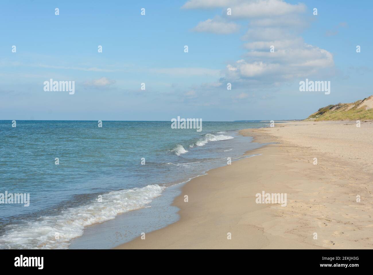 Weiche Wellen mit weißem Schaum am Ufer des Sandes. Urlaubs- und Reisekonzept. Stockfoto