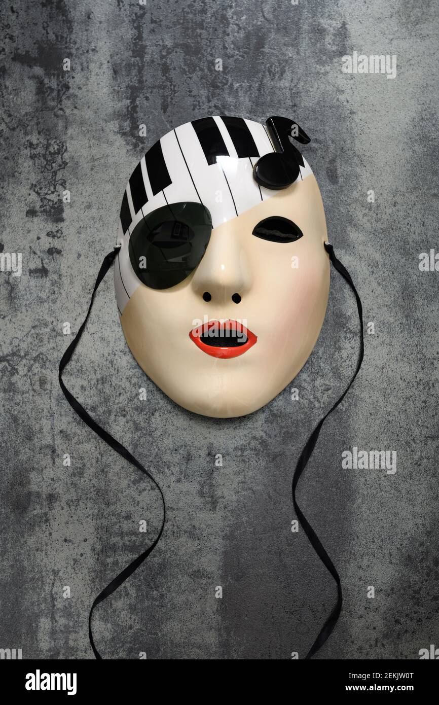 Porzellanmaske einer weiblichen Muse mit Tastatur und Hinweis auf einer Steinfliese Stockfoto